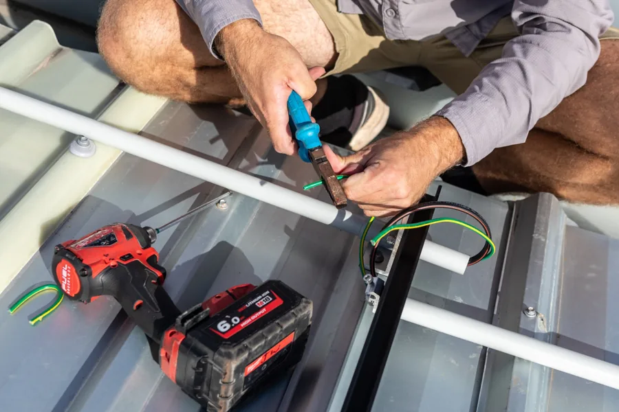Solar installer preparing electrical cabling during a rooftop solar installation on the Gold Coast